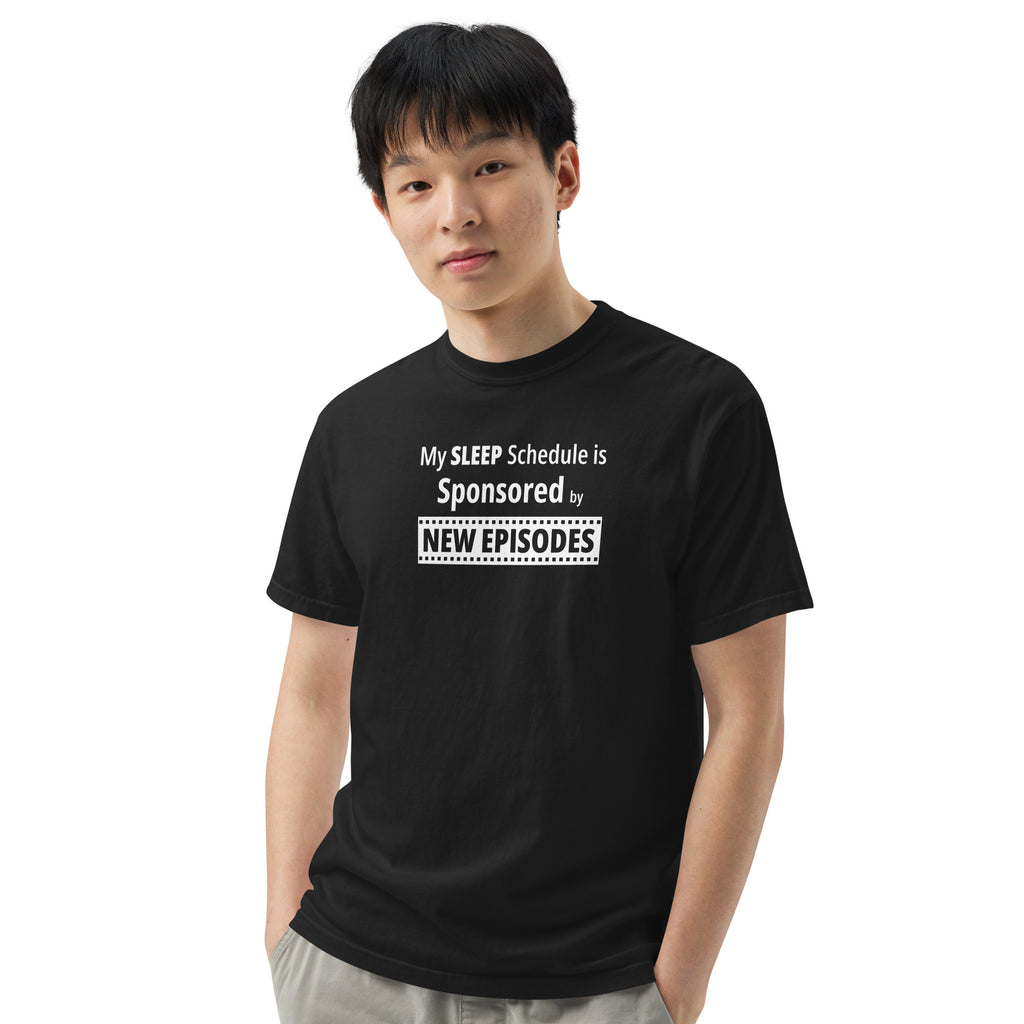 Person wearing a black t-shirt with humorous, funny, witty 'My Sleep Schedule is Sponsored by New Episodes' text design on a white background