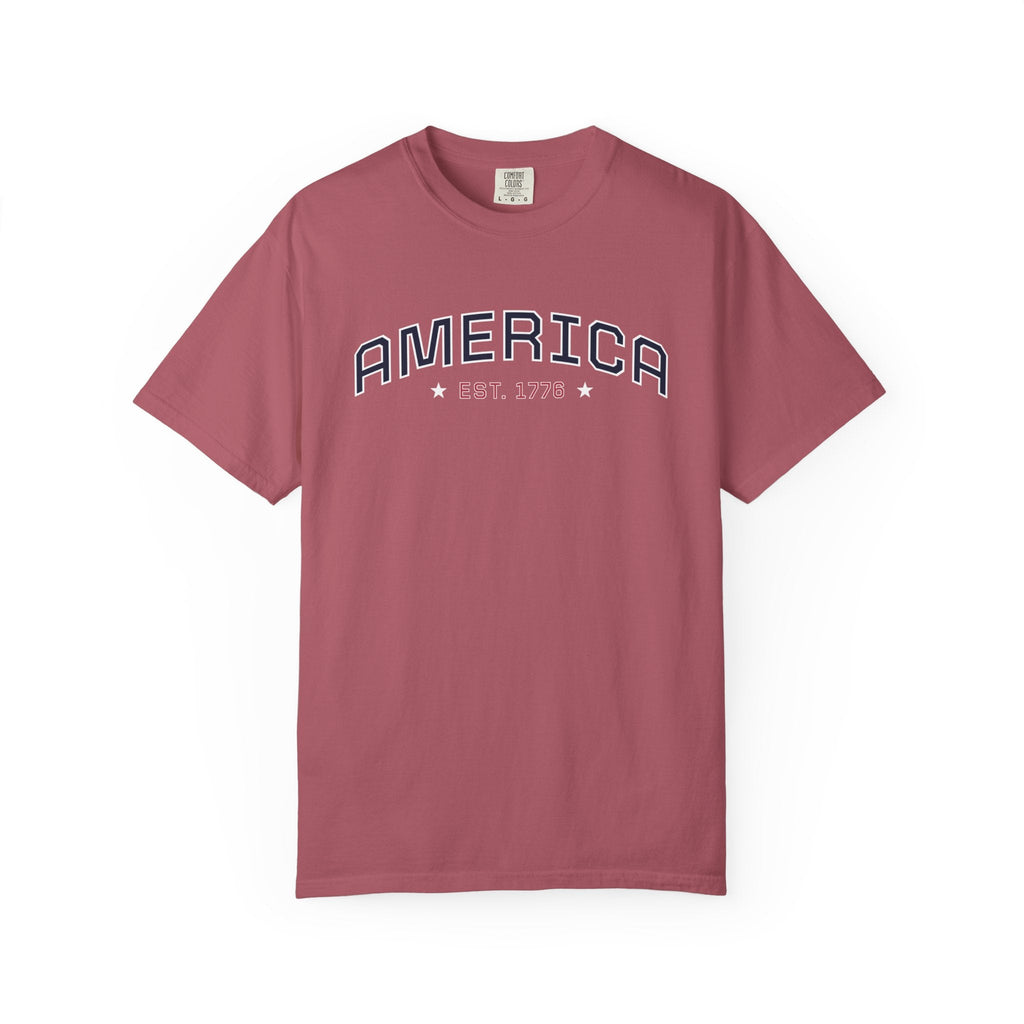 Crimson t-shirt with 'AMERICA EST. 1776' typography design in varsity style on a white background