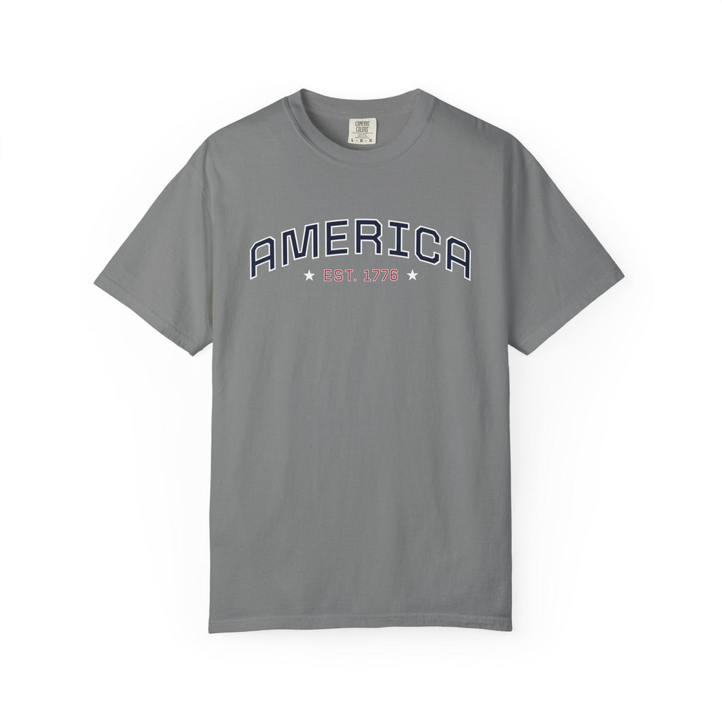 Grey t-shirt with 'AMERICA EST. 1776' typography design in varsity style on a white background