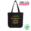 Black tote bag with yellow humorous anime text and free shipping and eco-friendly icons on a white background