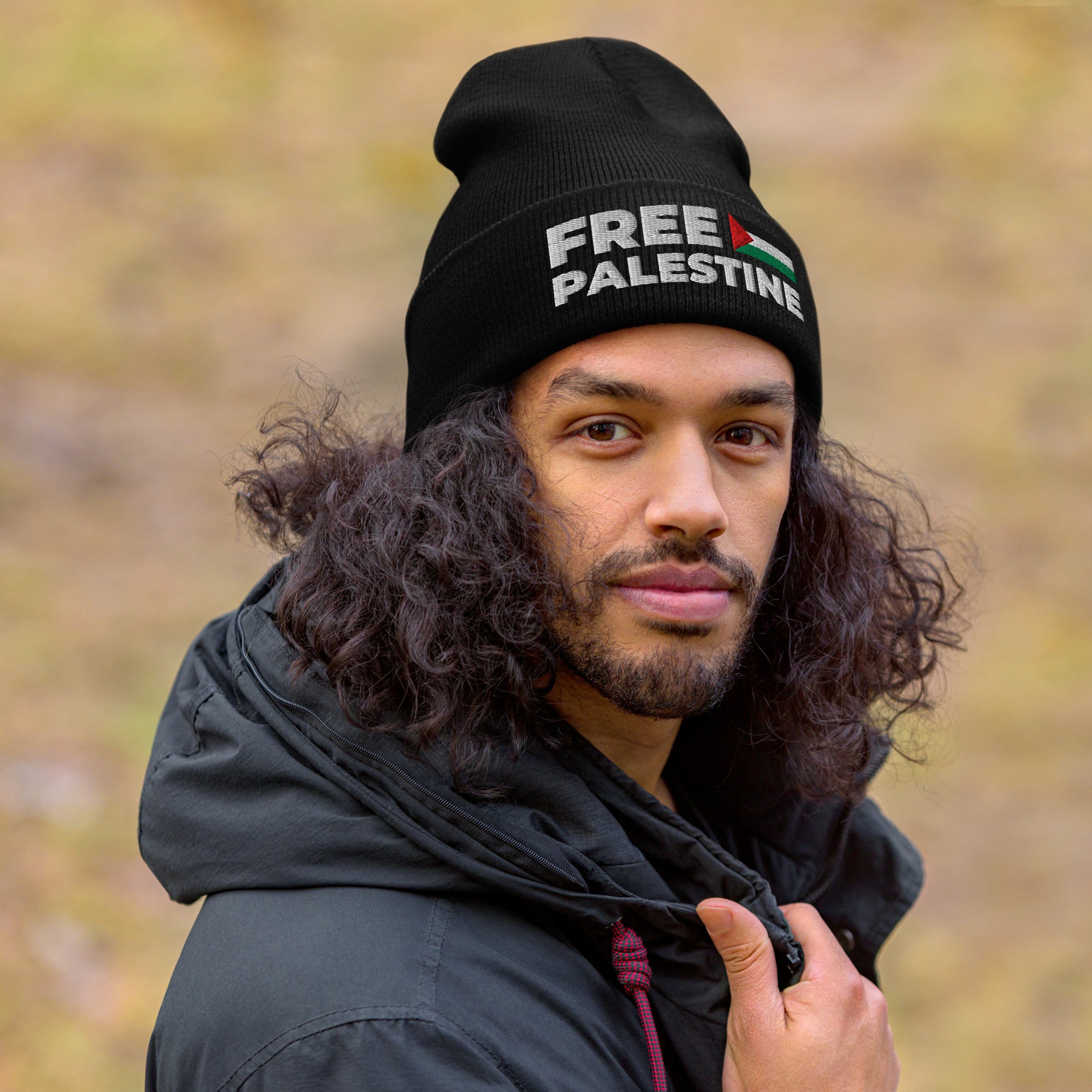 Person wearing a black beanie with 'Free Palestine' text outdoors