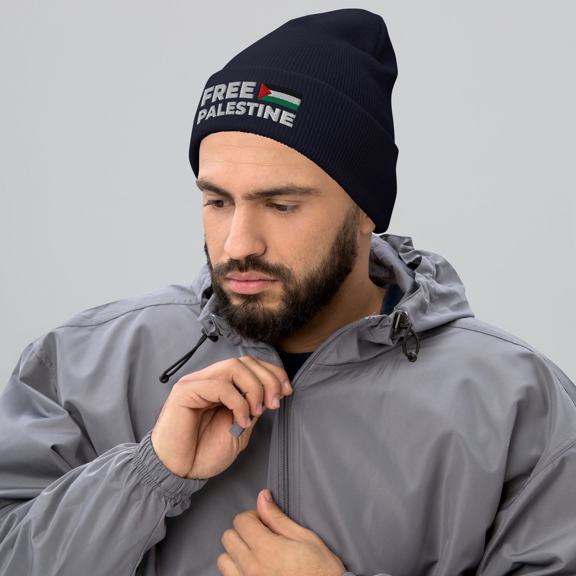 Man wearing a beanie with 'Free Palestine' text and a flag design, looking down.