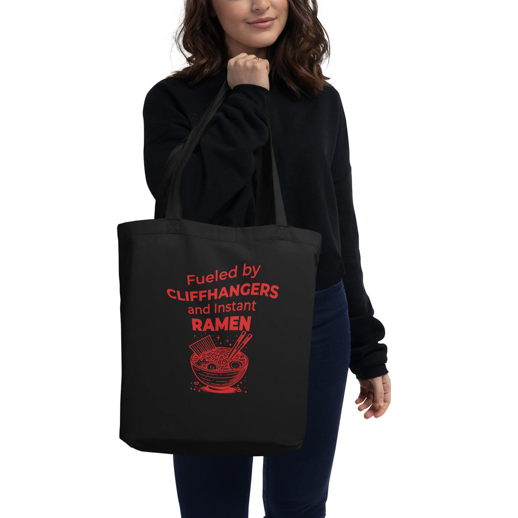 Person holding a black tote bag with red text and graphic design.