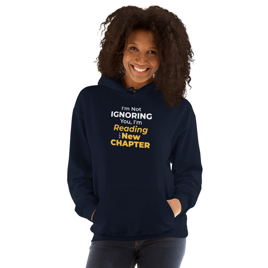 Person wearing a navy hoodie with humorous 'I'm Not Ignoring You, I'm Reading the New Chapter' text design on a white background