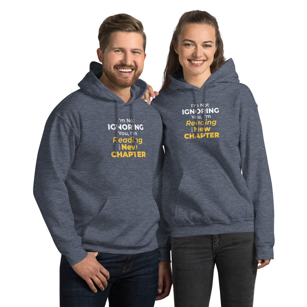 Two people wearing matching blue hoodies with humorous 'I'm Not Ignoring You, I'm Reading the New Chapter' text on a white background