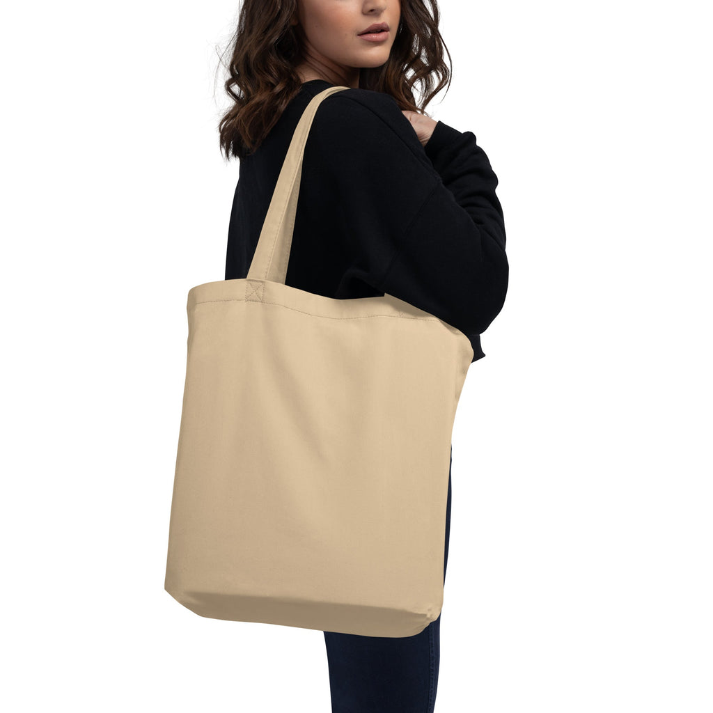Beige tote bag held by a person on a white background