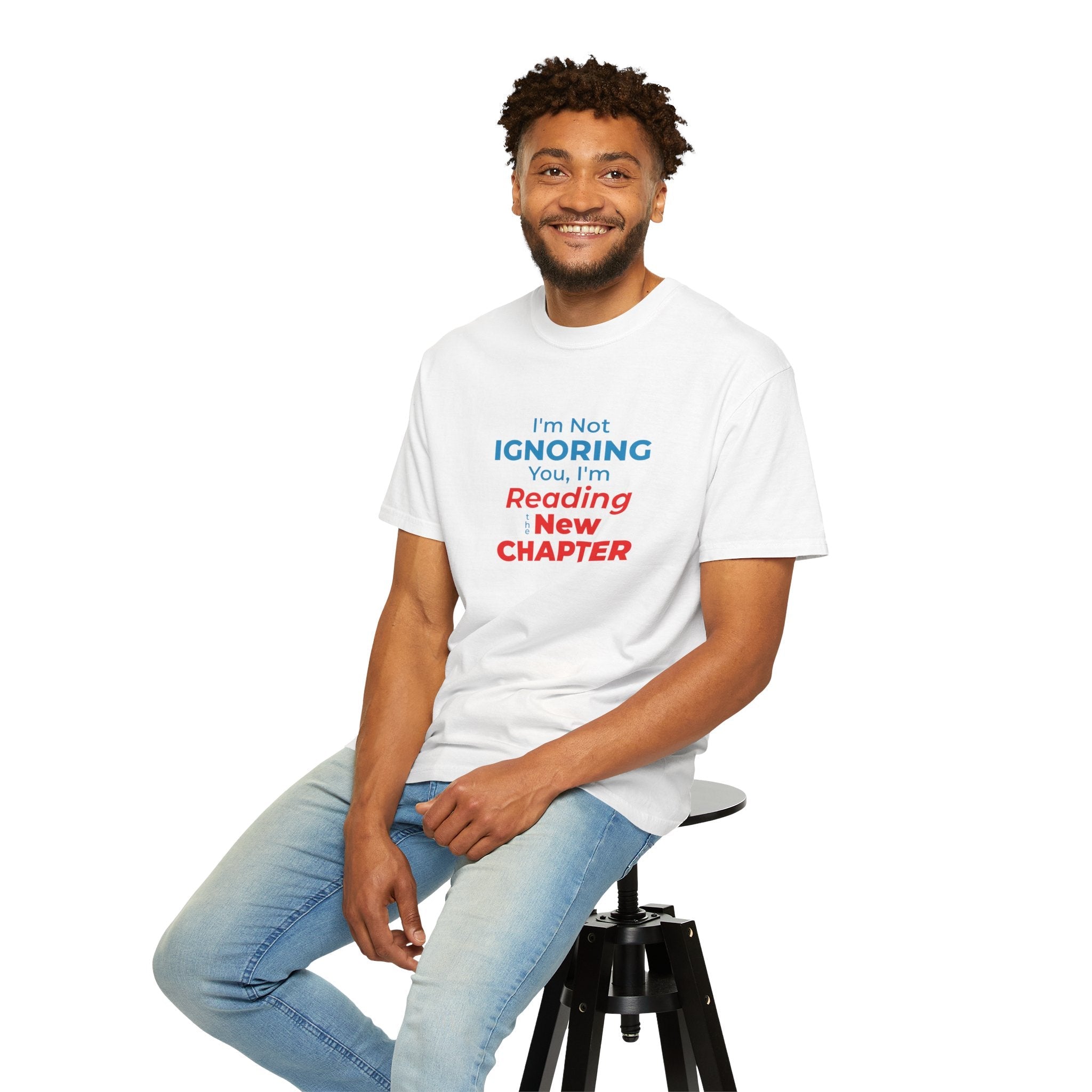 A man wearing white t-shirt with text 'I'm Not Ignoring You, I'm Reading the New Chapter' on a white background