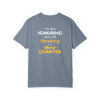 Blue Jean t-shirt with text 'I'm Not Ignoring You, I'm Reading the New Chapter' on the back side on a white background