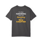 Graphite t-shirt with text 'I'm Not Ignoring You, I'm Reading the New Chapter' on the back side on a white background