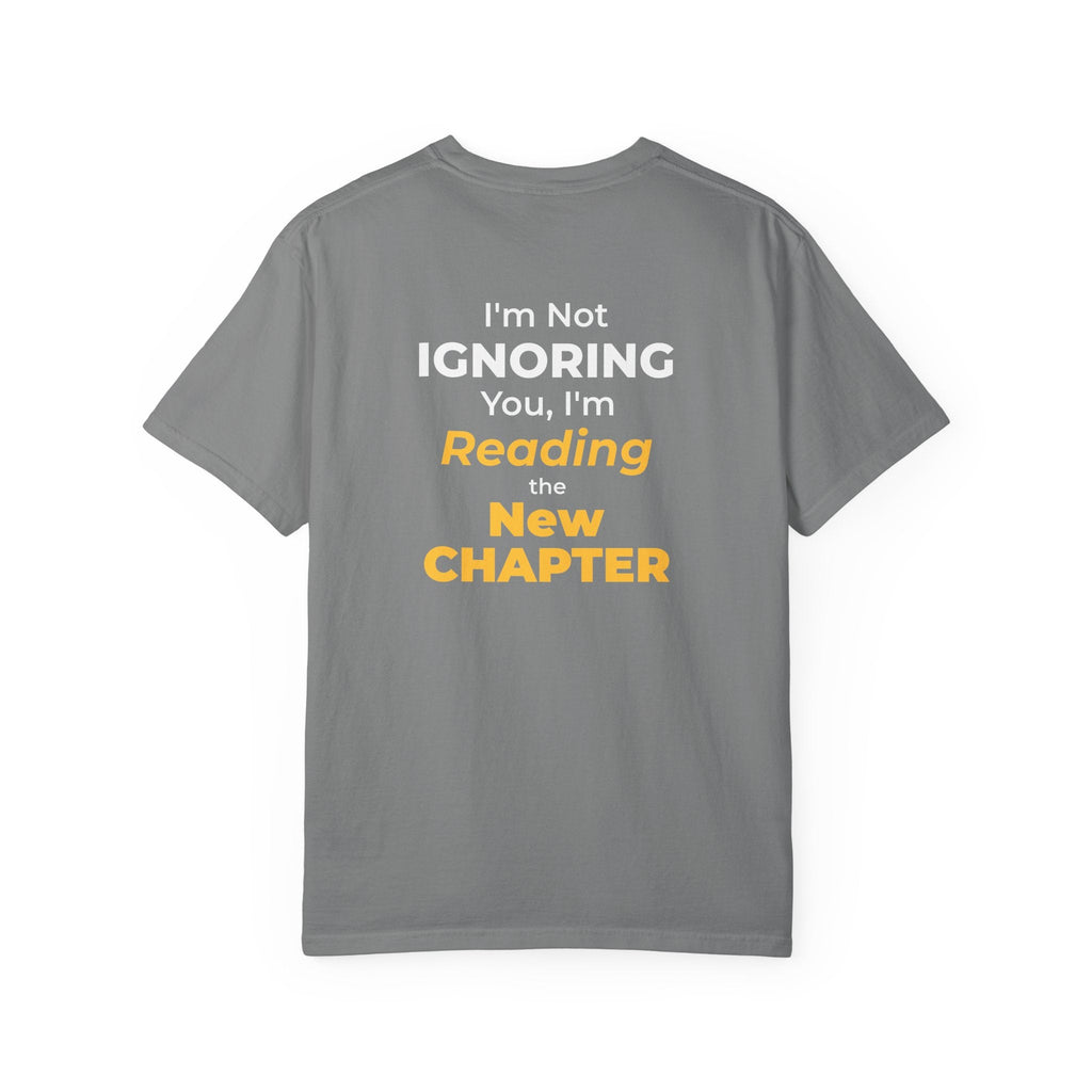 Grey t-shirt with text 'I'm Not Ignoring You, I'm Reading the New Chapter' on the back side on a white background