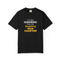 Black t-shirt with text 'I'm Not Ignoring You, I'm Reading the New Chapter' on a white background