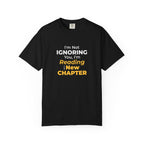 Black t-shirt with text 'I'm Not Ignoring You, I'm Reading the New Chapter' on a white background