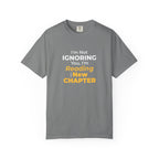 Grey t-shirt with text 'I'm Not Ignoring You, I'm Reading the New Chapter' on a white background