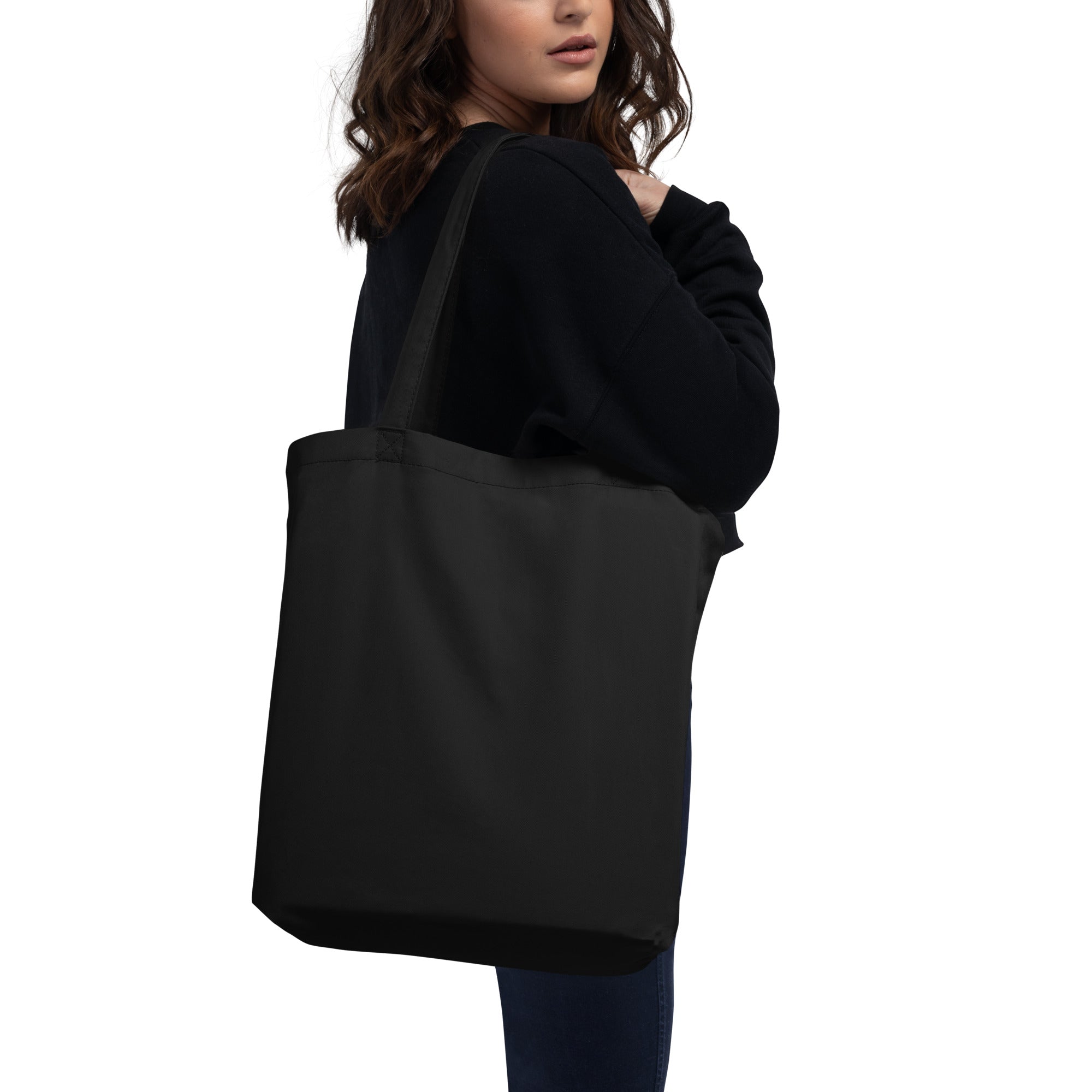 Person holding a black tote bag on a white background