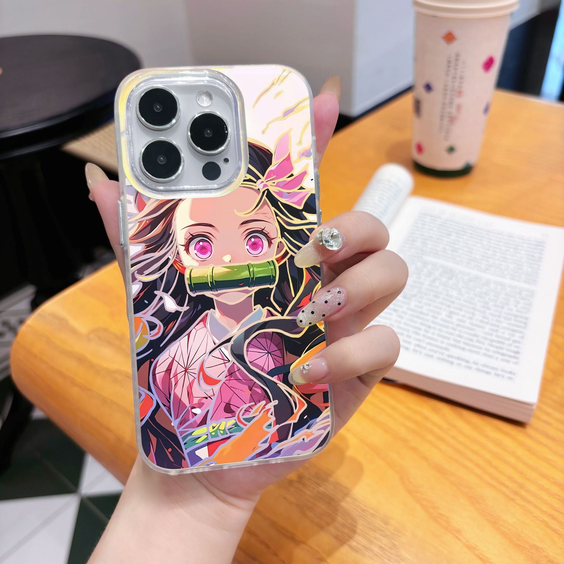 Phone case with anime Kimetsu No Yaiba Demon Slayer Nezuko Kamado character design held by a hand on a wooden table.