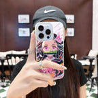 Person holding a phone with a colorful case featuring an anime Kimetsu No Yaiba Demon Slayer Nezuko Kamado character in a blurred indoor setting.