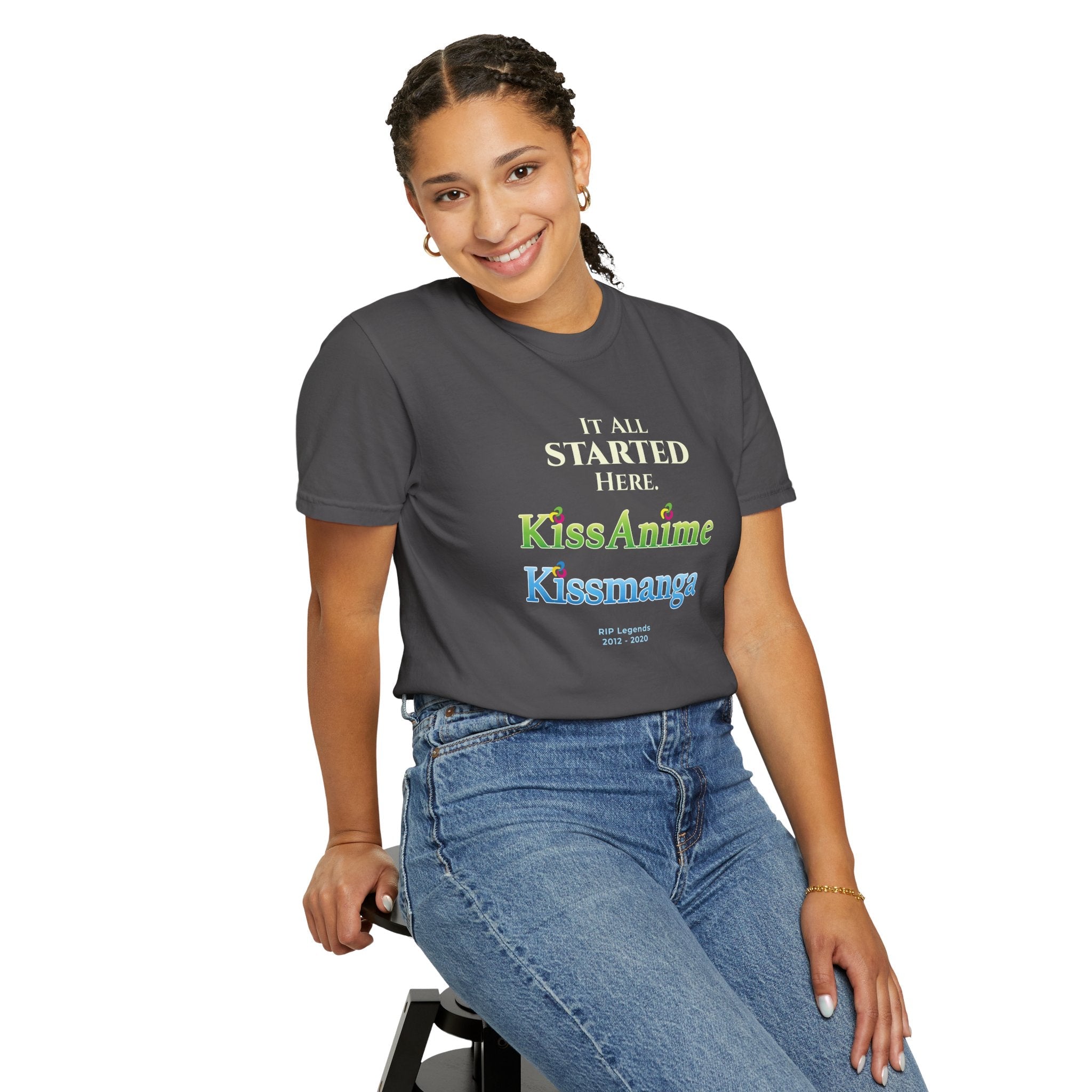 Person wearing a dark gray t-shirt with tribute text and kissanime kissmanga logo, sitting on a stool against a white background