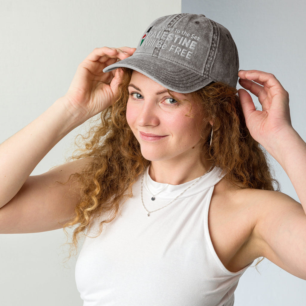 Woman wearing a gray cap with text, posing against a plain background