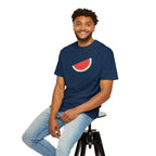 Man wearing a navy blue t-shirt with a watermelon design, sitting on a stool against a white background.