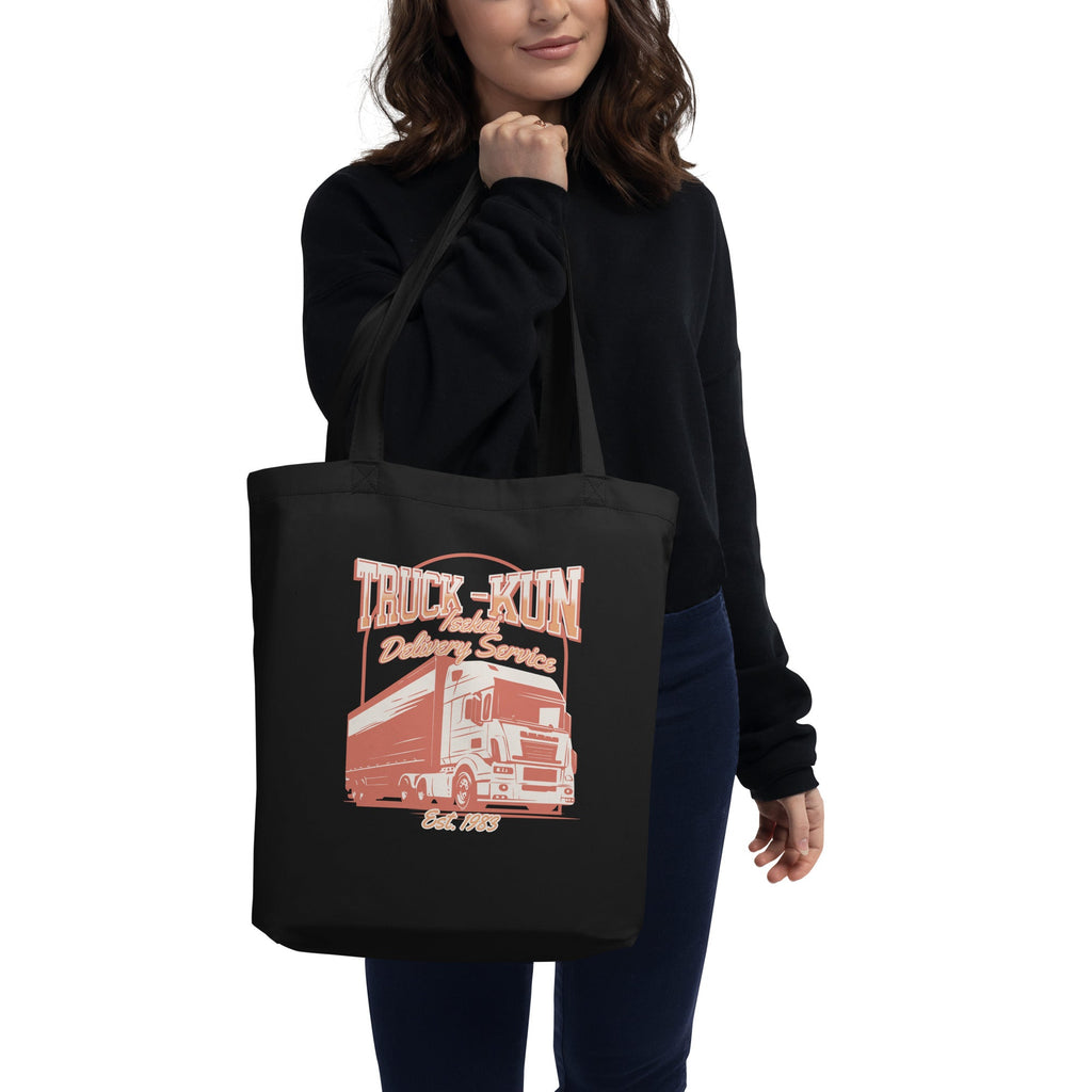 Person holding a black tote bag with an isekai truck-kun design and text on a white background
