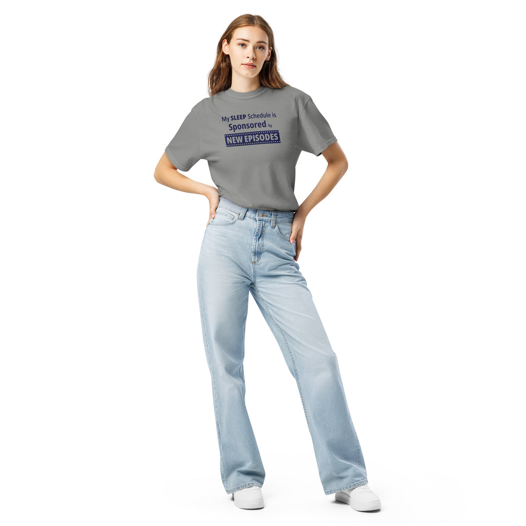 Person wearing a gray t-shirt and light blue jeans with funny, witty 'My Sleep Schedule is Sponsored by New Episodes' text design on a white background