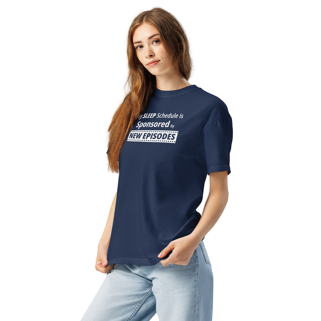 Person wearing a navy blue t-shirt with funny, witty 'My Sleep Schedule is Sponsored by New Episodes' text design on a white background