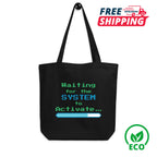 Black tote bag with 'Waiting for the SYSTEM to Activate' in 8-bit digital text design, free shipping icon, and eco-friendly logo on a white background
